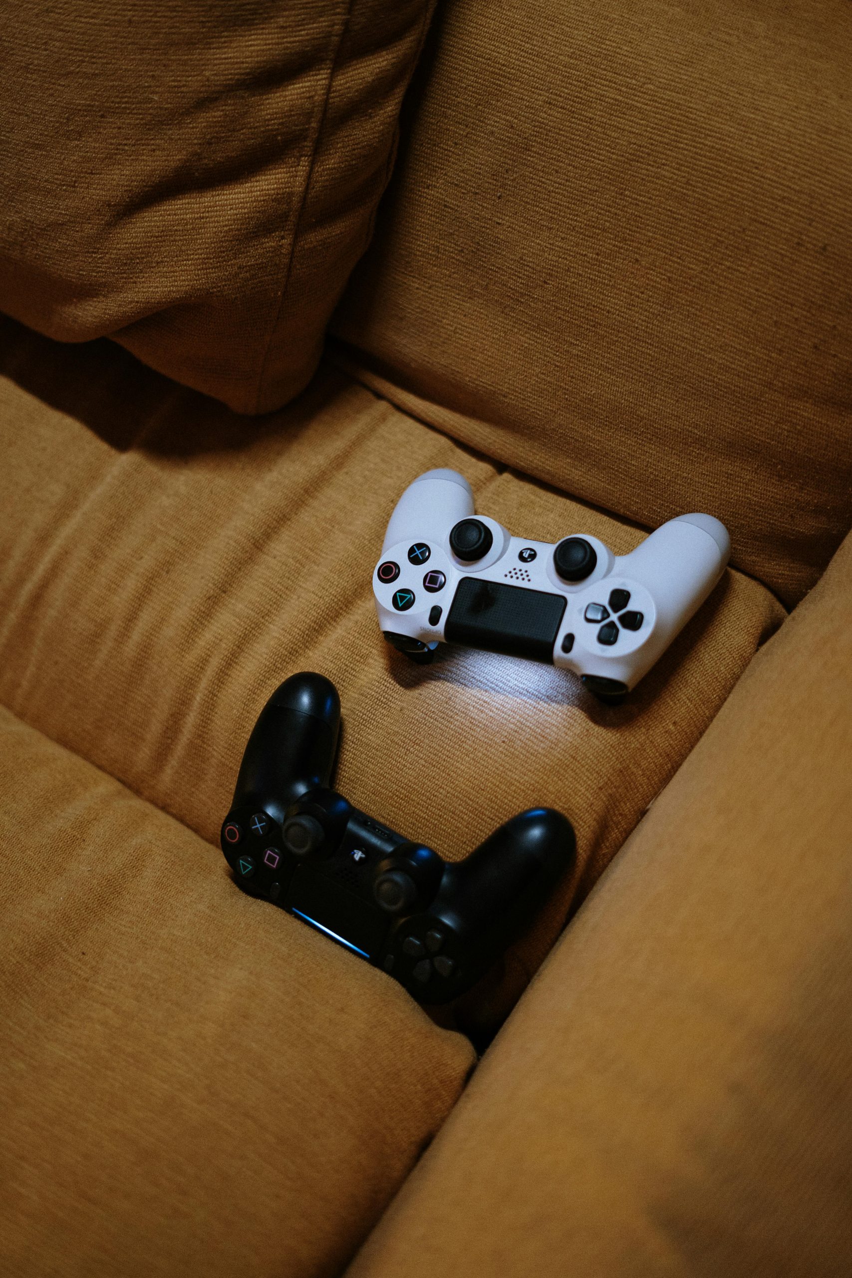 A cozy setting with black and white game controllers on a brown sofa. Perfect for leisure and gaming enthusiasts.